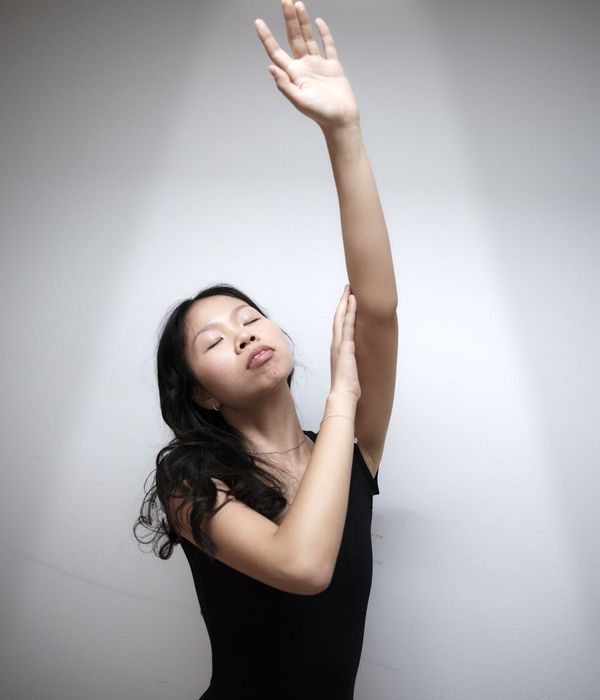 Woman performing a fluid cardio movement in a minimalist studio.